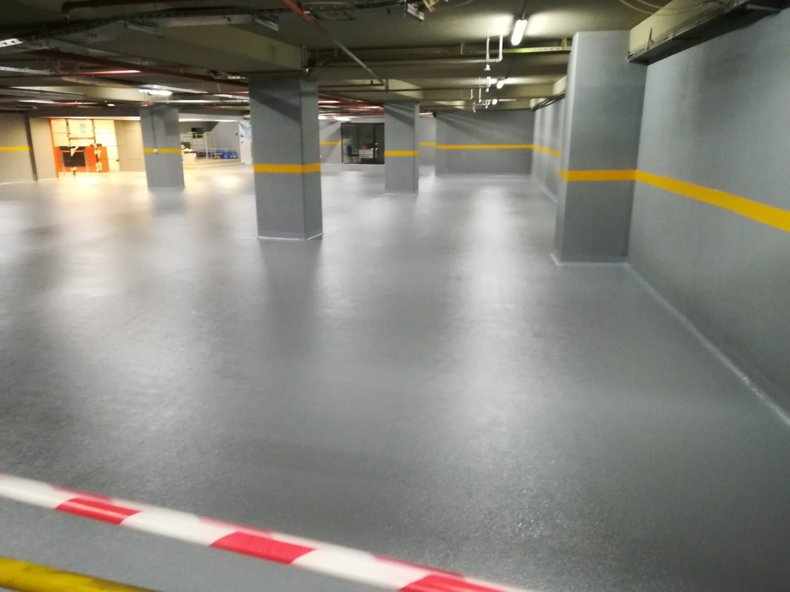 Kapalı otoparkta gri epoksi zemin ve sarı şerit